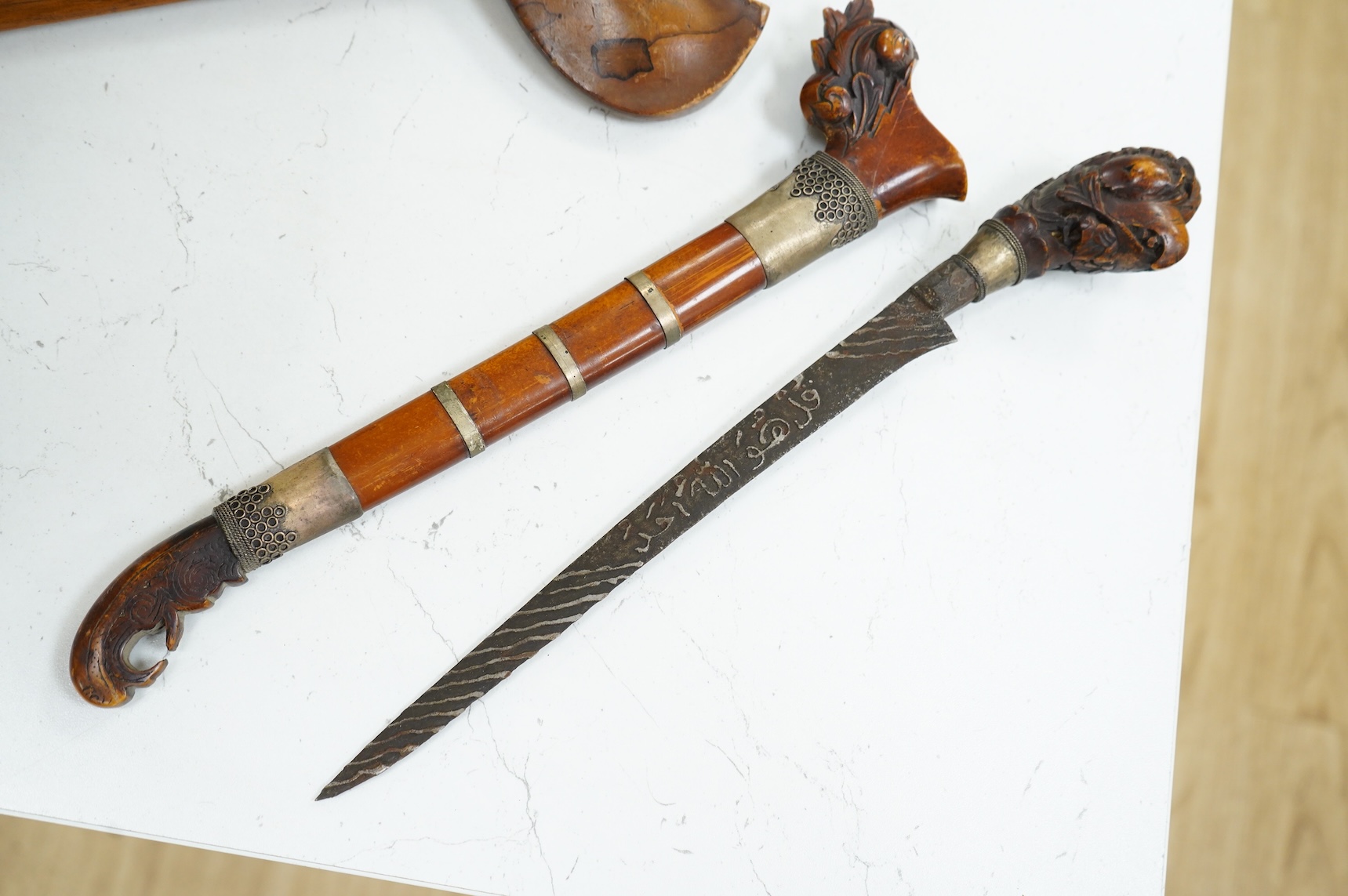 A Javanese dagger kris with straight pamor blade, wooden hilt carved as raksha, in its wooden sheath, together with a decorative dagger bade-bade, with etched blade